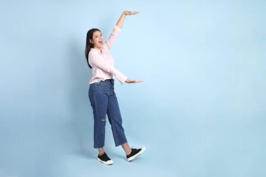 Mavi arka planda sıradan giyinmiş Asyalı kadın..