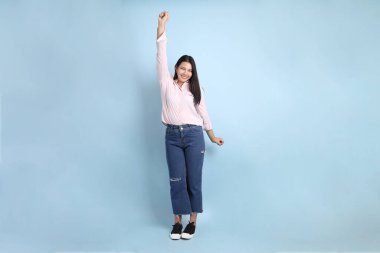 Mavi arka planda sıradan giyinmiş Asyalı kadın..