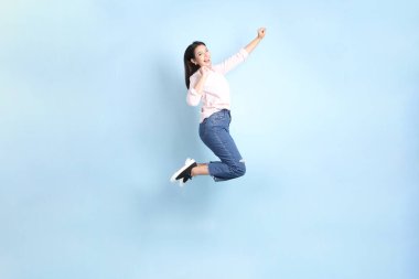 Mavi arka planda sıradan giyinmiş Asyalı kadın..