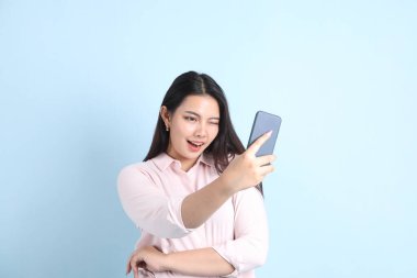 Mavi arka planda sıradan giyinmiş Asyalı kadın..