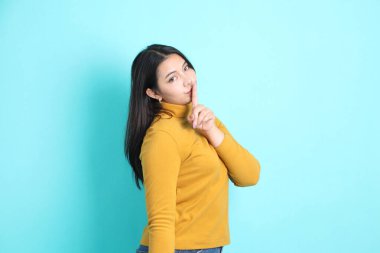 Yeşil arka planda sıradan giyinmiş Asyalı kadın..