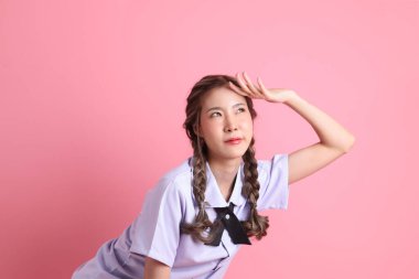 Pembe arka planda duran Taylandlı öğrenci üniformalı Asyalı kız..