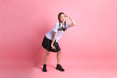 Pembe arka planda duran Taylandlı öğrenci üniformalı Asyalı kız..