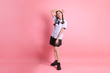 Pembe arka planda duran Taylandlı öğrenci üniformalı Asyalı kız..