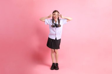 Pembe arka planda duran Taylandlı öğrenci üniformalı Asyalı kız..