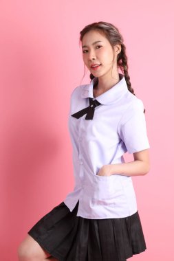 Pembe arka planda duran Taylandlı öğrenci üniformalı Asyalı kız..