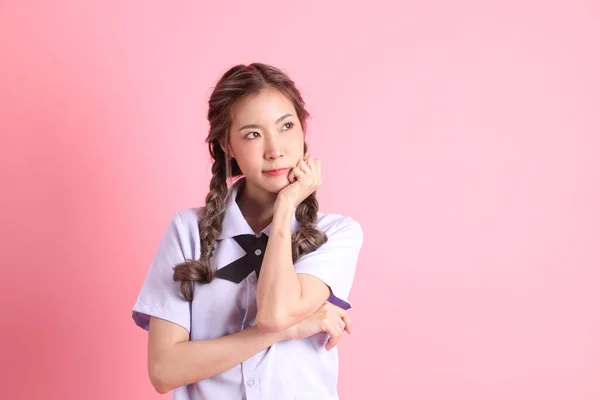 身穿泰国学生制服的亚洲女孩站在粉色的背景上 — 图库照片