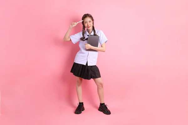 ピンクの背景に立っているタイの学生制服のアジアの少女 — ストック写真