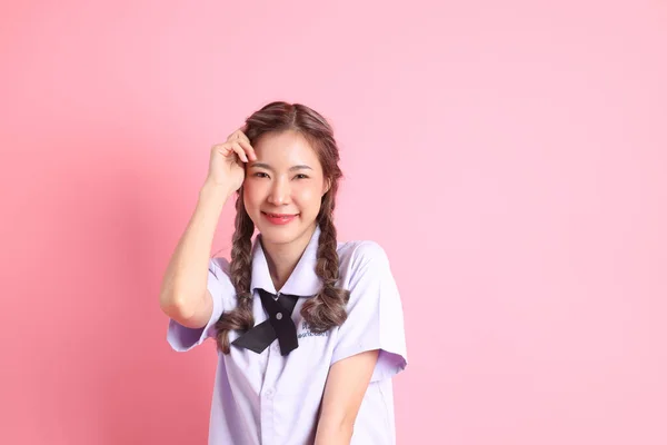 身穿泰国学生制服的亚洲女孩站在粉色的背景上 — 图库照片