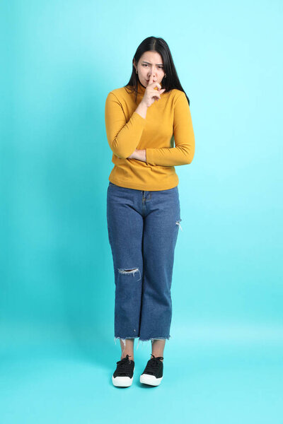 The Asian woman in casual clothes standing on the green background.
