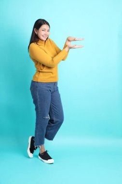 Yeşil arka planda sıradan giyinmiş Asyalı kadın..