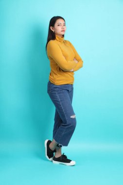 Yeşil arka planda sıradan giyinmiş Asyalı kadın..