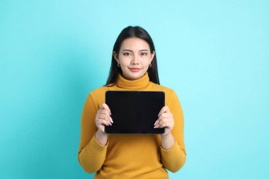 Yeşil arka planda sıradan giyinmiş Asyalı kadın..