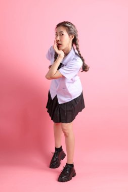 Pembe arka planda duran Taylandlı öğrenci üniformalı Asyalı kız..