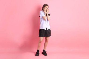 Pembe arka planda duran Taylandlı öğrenci üniformalı Asyalı kız..