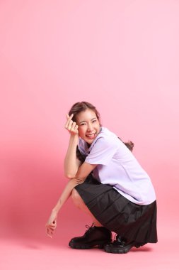 Pembe arka planda oturan Taylandlı öğrenci üniformalı Asyalı kız..