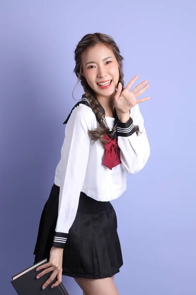 紫色の背景に立っている日本の学生制服のアジアの少女 — ストック写真