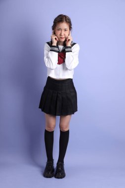 Mor arka planda duran Japon öğrenci üniformalı Asyalı kız..