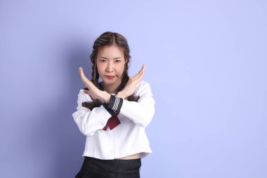 Mor arka planda duran Japon öğrenci üniformalı Asyalı kız..