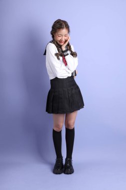 Mor arka planda duran Japon öğrenci üniformalı Asyalı kız..