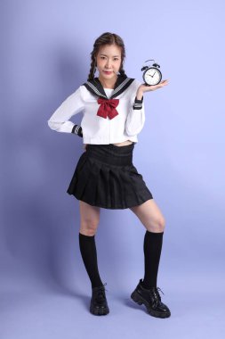 Mor arka planda duran Japon öğrenci üniformalı Asyalı kız..