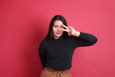 Kırmızı arka planda duran siyah elbiseli Asyalı kadın..