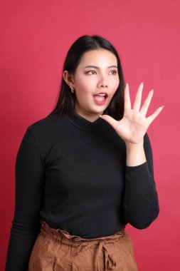 Kırmızı arka planda duran siyah elbiseli Asyalı kadın..