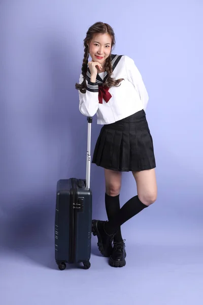 身穿日本校服的亚洲女孩站在紫色的背景上 — 图库照片