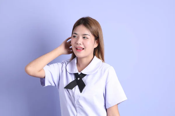 身穿泰国学生制服的亚洲女孩站在紫色的背景上 — 图库照片