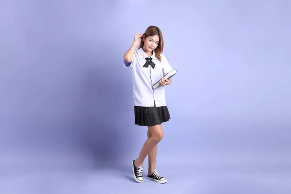 紫色の背景に立っているタイの学生制服のアジアの少女 — ストック写真