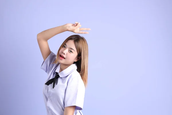 紫色の背景に立っているタイの学生制服のアジアの少女 — ストック写真