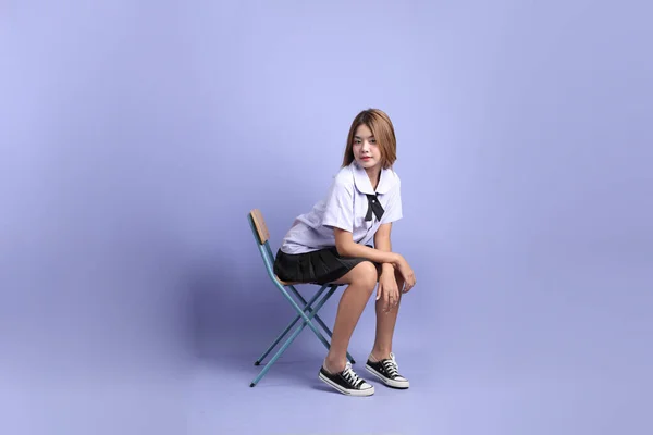 Asijská Dívka Thajské Studentské Uniformě Sedí Židle Fialovém Pozadí — Stock fotografie
