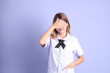 Mor arka planda duran Taylandlı öğrenci üniformalı Asyalı kız..