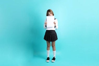 Yeşil arka planda duran Japon öğrenci üniformalı Asyalı kız..