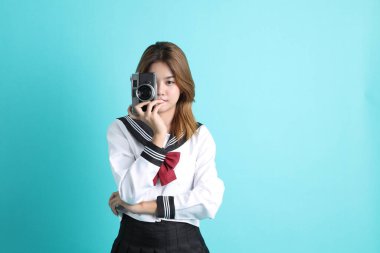 Yeşil arka planda duran Japon öğrenci üniformalı Asyalı kız..