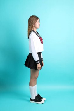 Yeşil arka planda duran Japon öğrenci üniformalı Asyalı kız..