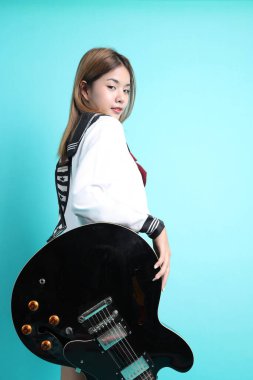 Yeşil arka planda duran Japon öğrenci üniformalı Asyalı kız..