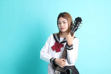 Yeşil arka planda duran Japon öğrenci üniformalı Asyalı kız..