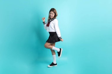 Yeşil arka planda duran Japon öğrenci üniformalı Asyalı kız..