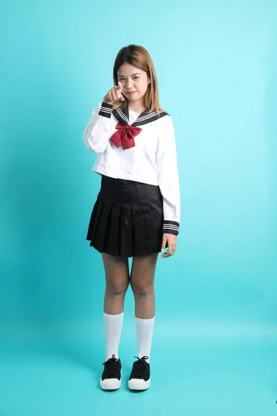 身穿日本校服的亚洲女孩站在绿色的背景上 — 图库照片