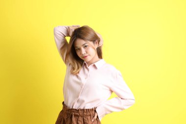 Sarı arka planda sıradan giyinmiş Asyalı kadın..