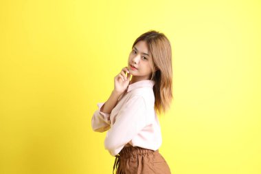 Sarı arka planda sıradan giyinmiş Asyalı kadın..