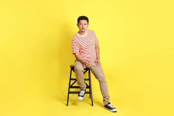 Sarı Arka Planda Oturan Sıradan Giysili Yetişkin Asyalı Adam — Stok fotoğraf