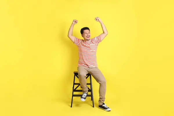 Sarı Arka Planda Oturan Sıradan Giysili Yetişkin Asyalı Adam — Stok fotoğraf