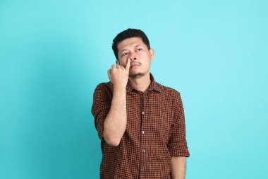 Yeşil arka planda duran şık giysili Asyalı yetişkin adam..