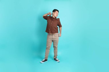 Yeşil arka planda duran şık giysili Asyalı yetişkin adam..