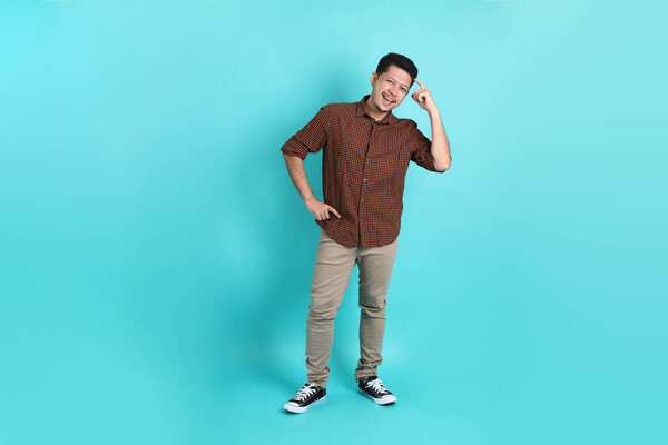The adult Asian man in smart casual clothes standing on the green background background.