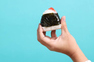 Asyalı adam yeşil arka planda Japon yemeklerini tutuyor..