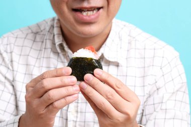 Yeşil arka planda onigiri yiyen Asyalı adam..