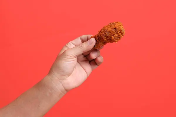 The Asian man hand holding the deep fly chicken fly on the orange background.